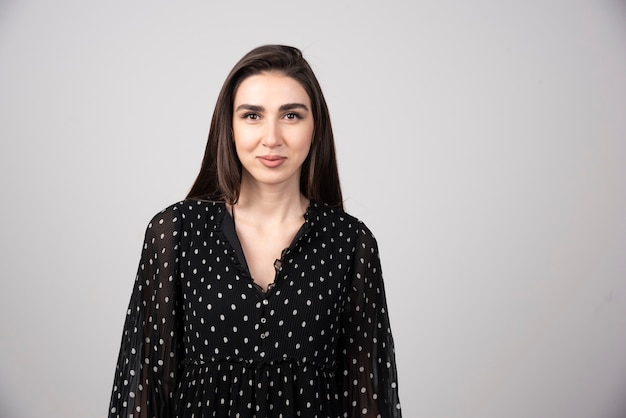 Woman in black dress standing on gray.