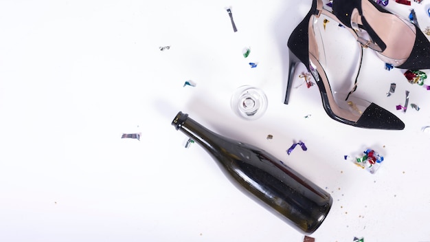 Woman black heels lying near bottle after party