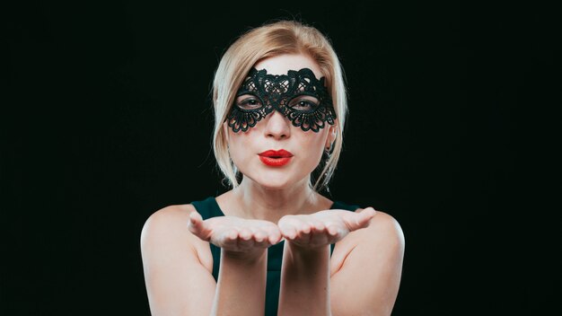 Woman in black mask blowing kiss