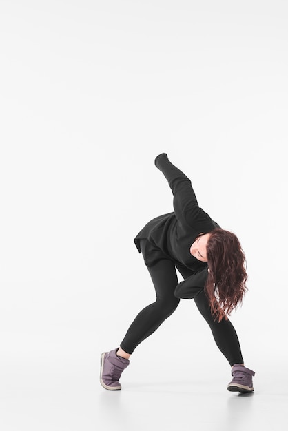 Woman in black outfit dancing against white backdrop