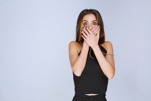 Woman in black shirt covering her face with hands. 