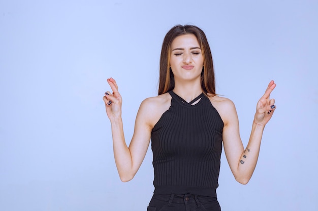 Woman in black shirt doing finger cross sign. 