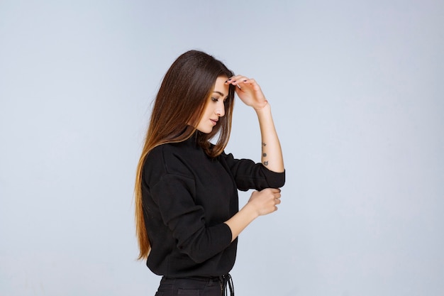 Donna in camicia nera che dà pose neutre e civettuole.