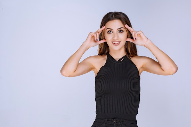 Woman in black shirt looking through her fingers. 