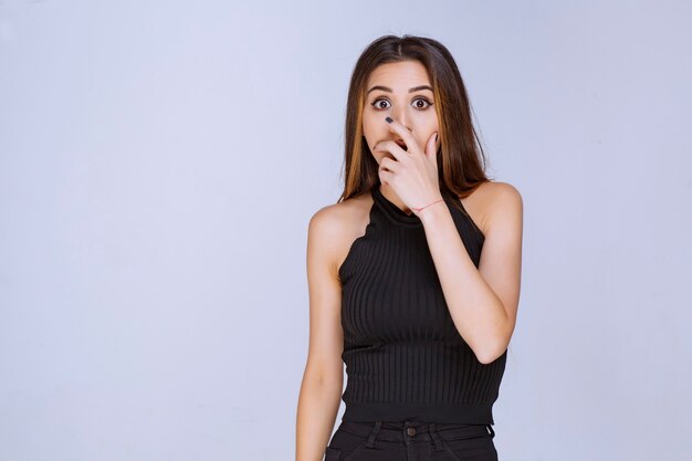 Woman in black shirt looks scared and terrified. 