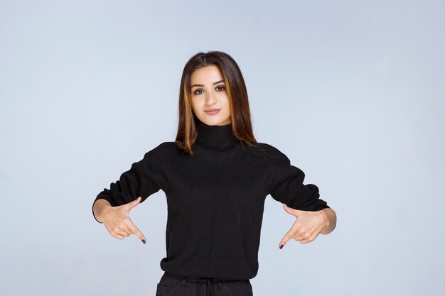 woman in black shirt pointing at downside. 