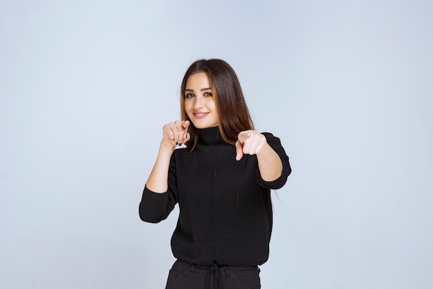 Donna in camicia nera che indica il suo partner avanti.