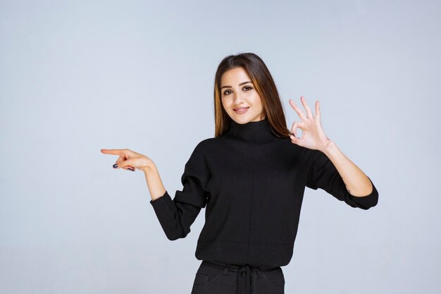 woman in black shirt pointing to the left and showing her emotions. 