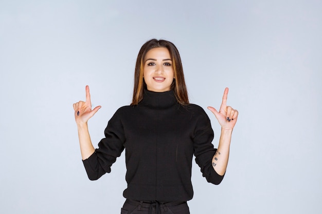 woman in black shirt pointing above. 