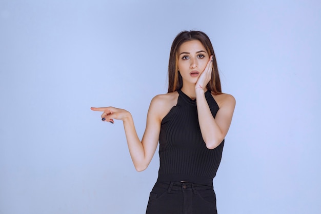 Free photo woman in black shirt showing something on the left.