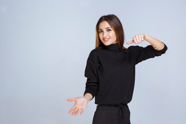 woman in black shirt showing thumb down sign. 