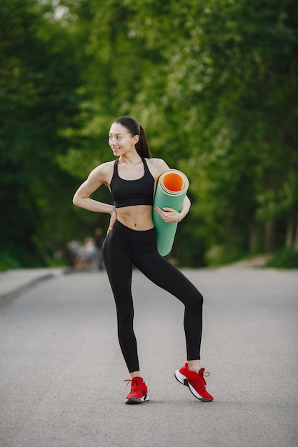 Woman in a black sportswear standing in a forest