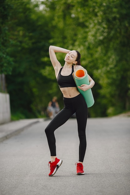 Woman in a black sportswear standing in a forest