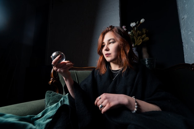 Woman in black suit holding crystal ball in her hands