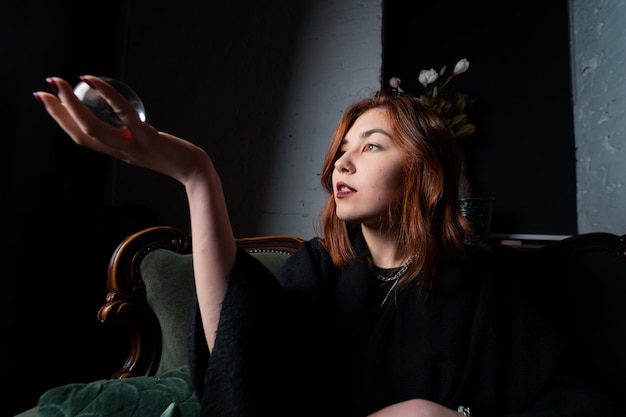 Free photo woman in black suit holding crystal ball