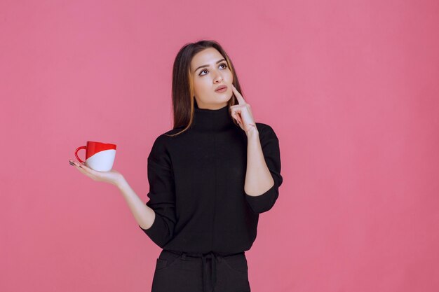 Woman in black sweater having coffee and thinking. 