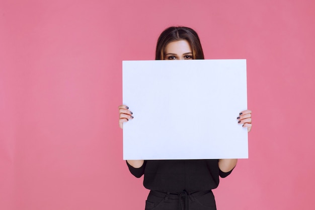 Woman in black sweater holding a square idea board. 