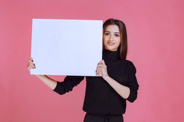 Free photo woman in black sweater holding a square idea board.