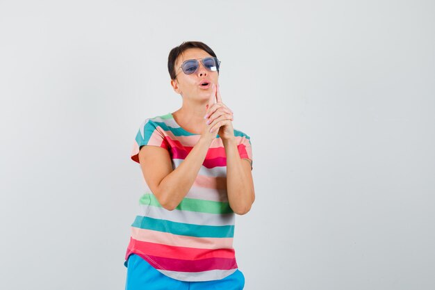 Woman blowing on finger pistol in striped t-shirt, pants and looking confident