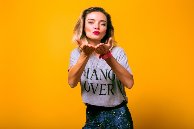 Woman blowing kiss at yellow wall