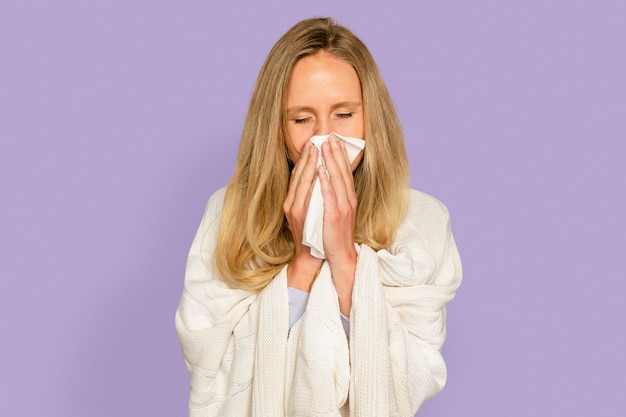 Woman blowing nose with blanket covering her