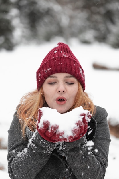 Woman blowing in a pile of snow
