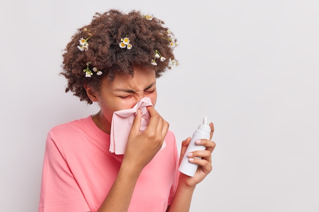 woman blows nose in tissue sprays aerosol has allergic reaction wears casual pink t shirt isolated on white 