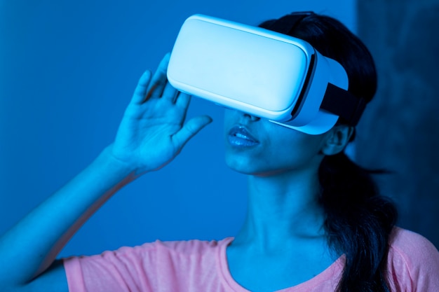 Женщина в синем свете с помощью гарнитуры виртуальной реальности