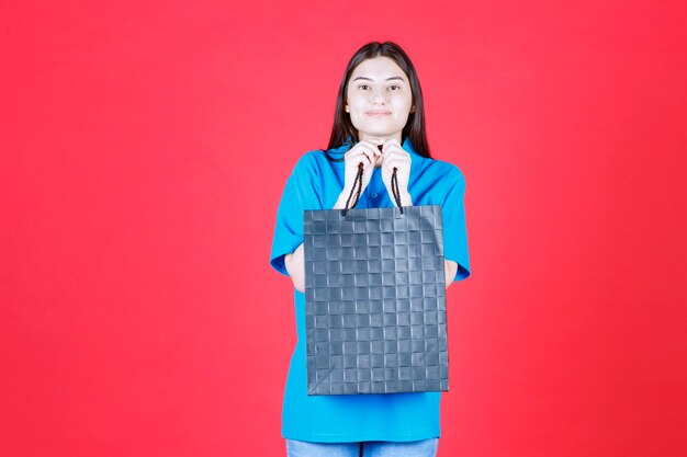 woman in blue shirt holding a purple shopping bag.