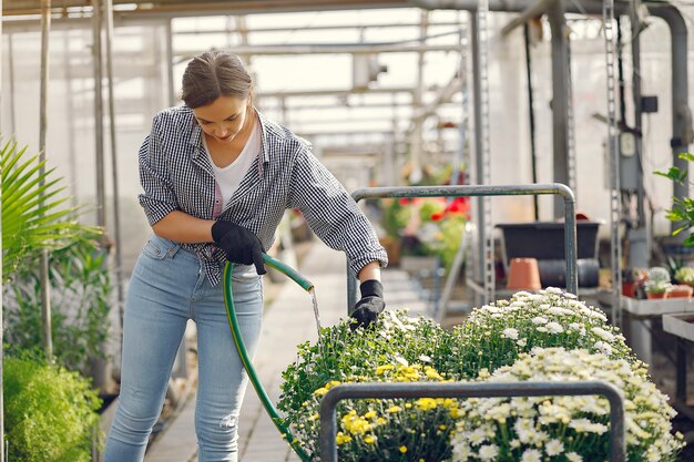 青いシャツを着た女性は植木鉢を注ぐ