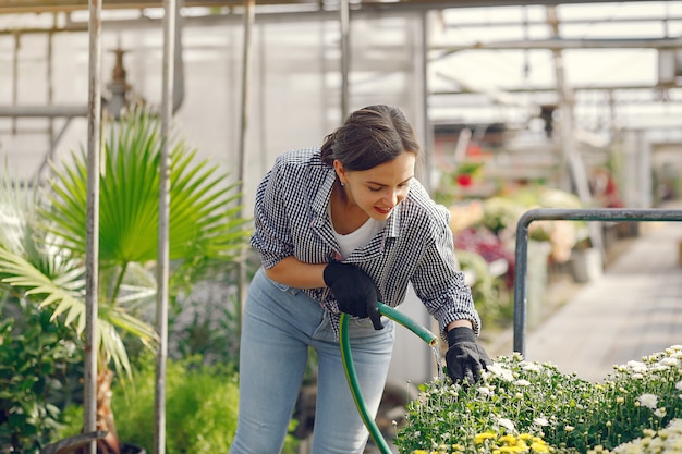 Woman in a blue shirt pours flowerpots