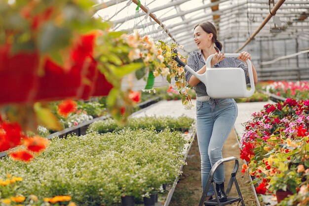 青いシャツを着た女性は植木鉢を注ぐ