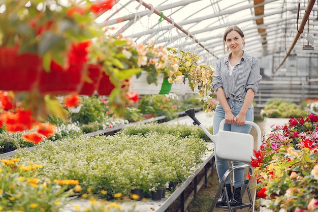 青いシャツを着た女性は植木鉢を注ぐ