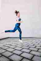 Free photo woman in blue sportswear leaping on street