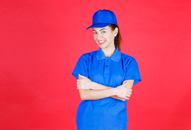긍정적이고 중립적인 포즈를 취하는 파란색 유니폼을 입은 여성.