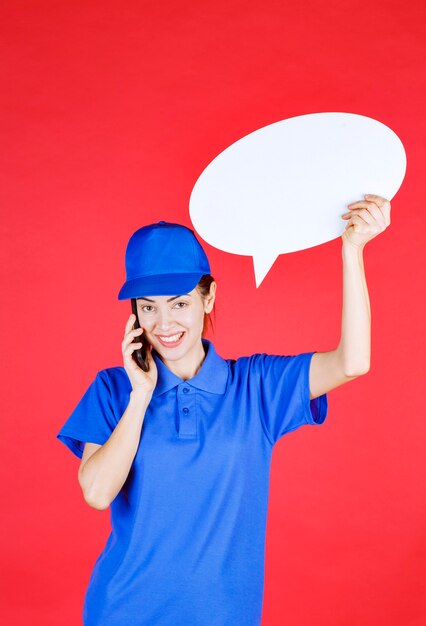 Woman in blue uniform holding an ovale idea board and talking to the phone. 
