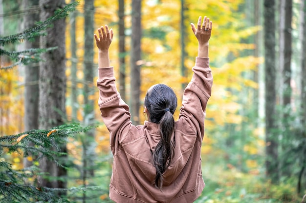 Woman on a blurred background of the autumn forest view from the back