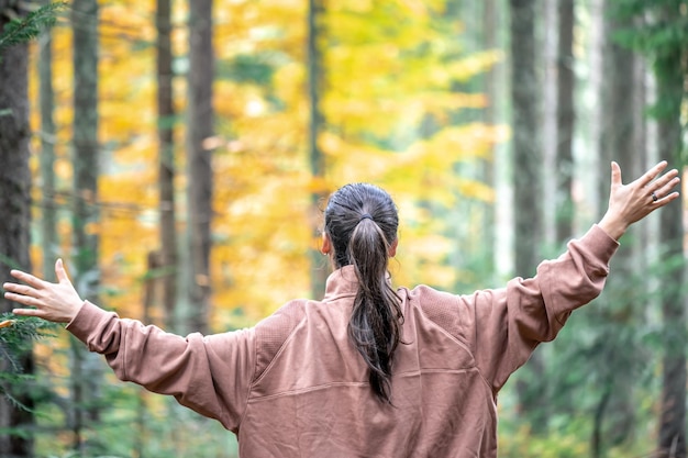 Woman on a blurred background of the autumn forest view from the back