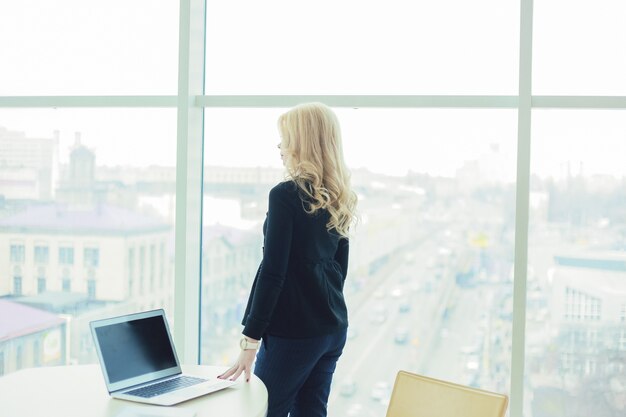 女性のボススタイルは、ノートパソコンの手のオフィスで働く