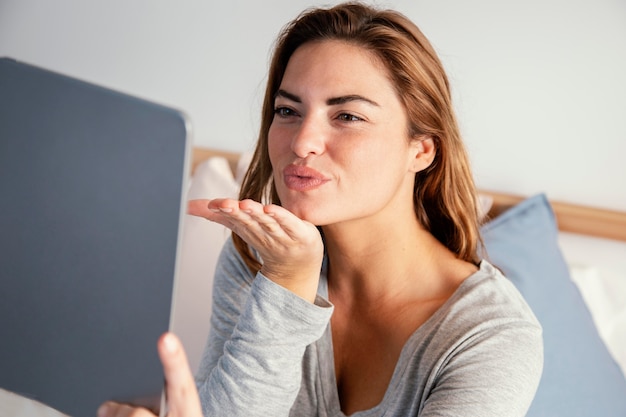 Woman bow kiss towards video call on tablet