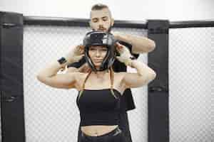Free photo woman boxing. beginner in a gym. lady in a black sportwear. woman with coach.