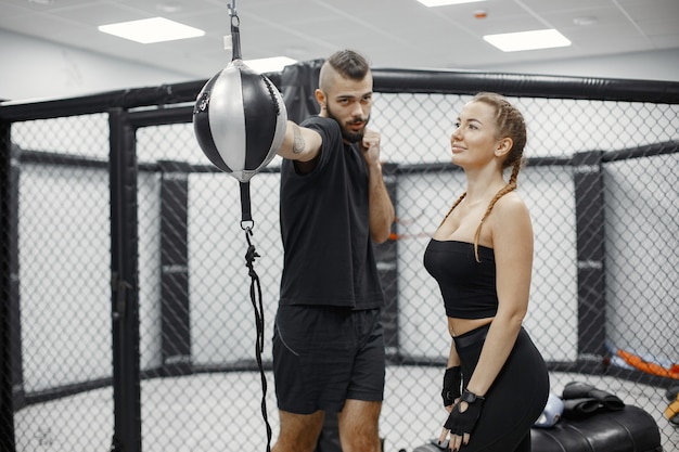 Foto gratuita boxe donna. principiante in palestra. signora in abbigliamento sportivo nero. donna con allenatore.