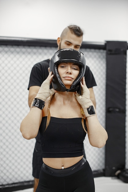 Free photo woman boxing. beginner in a gym. lady in a black sportwear. woman with coach.