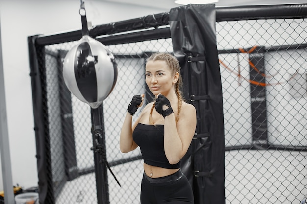 Woman boxing. Beginner in a gym. Lady in a black sportwear.