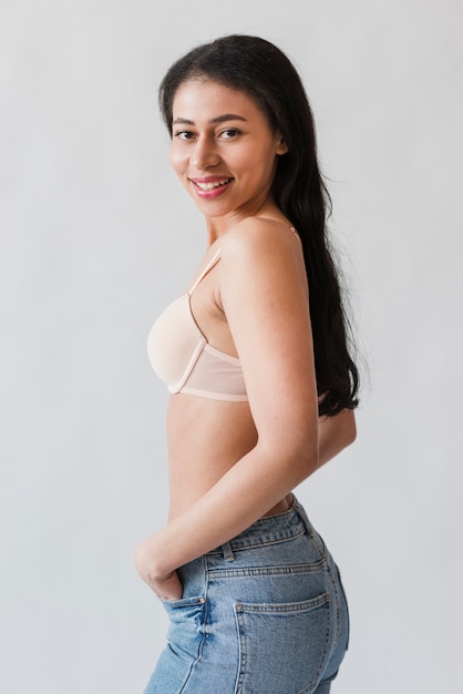 Woman in bra standing sideways smiling at camera