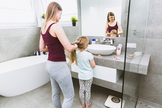 Woman braiding hair of daughter