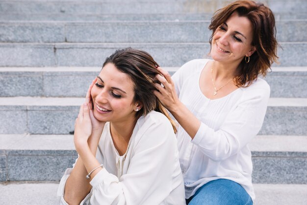 Woman braiding hair of woman