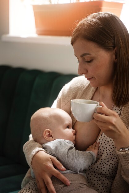 Woman breastfeeding baby indoors side view