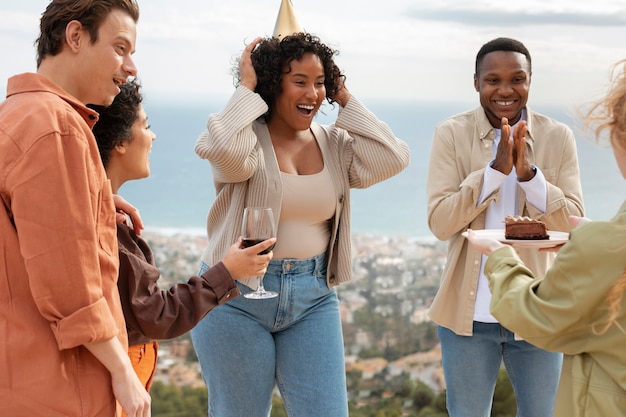 Free photo woman bringing cake to her friends during outdoor party