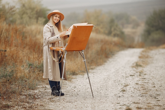 Woman in a brown coat painting in a field